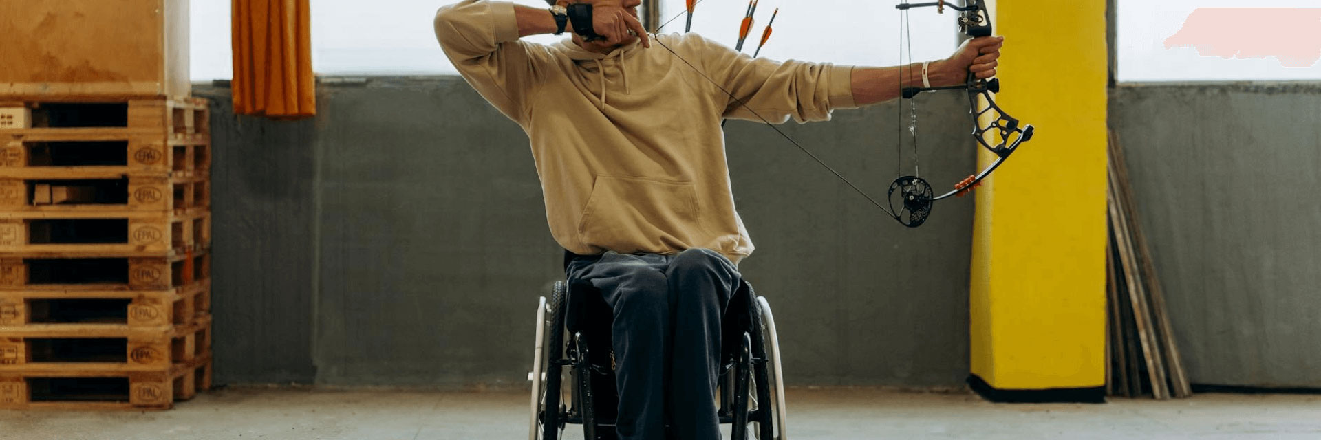 image of a person in a wheelchair practicing archery indoors