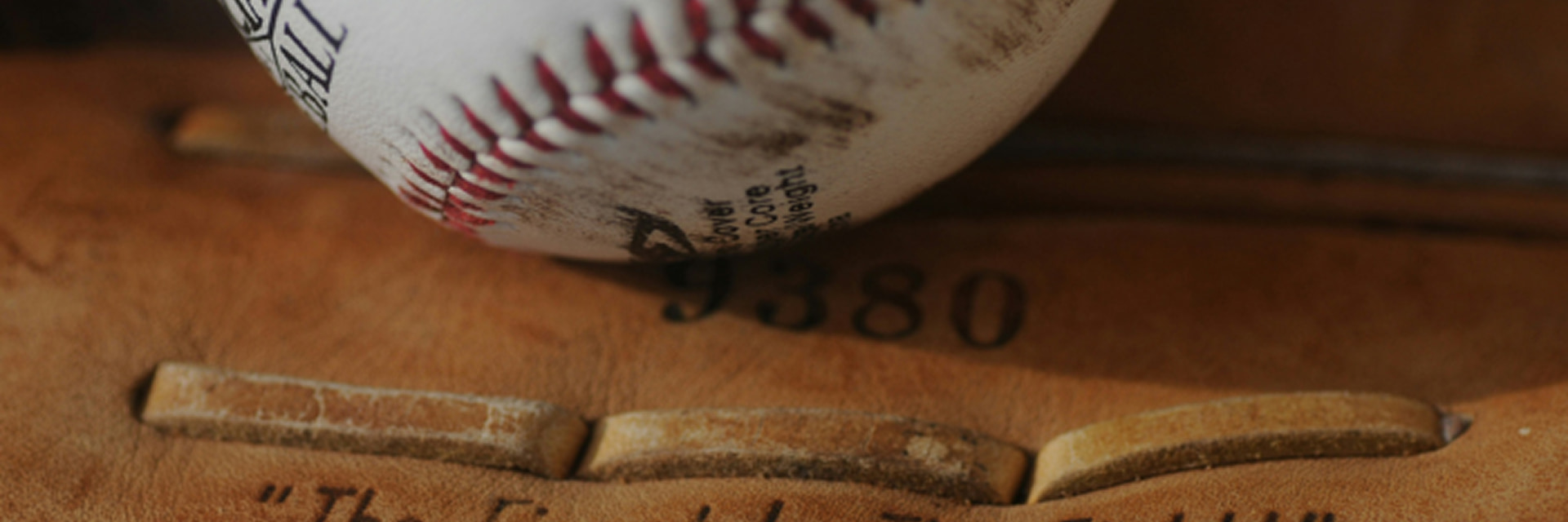image of a worn baseball resting in a leather catcher's mitt