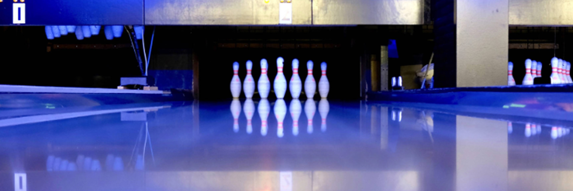 image of a bowling lane leading to a set of ten white bowling pins
