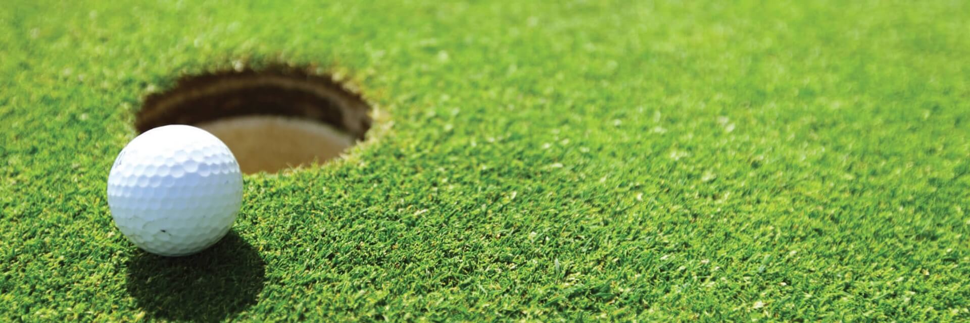 an image of a golf ball on a green, next to the hole, on a golf course.