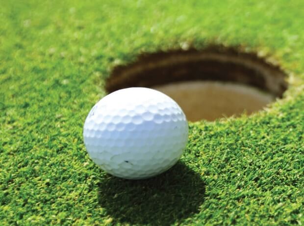 an image of a golf ball on a green, next to the hole, on a golf course.