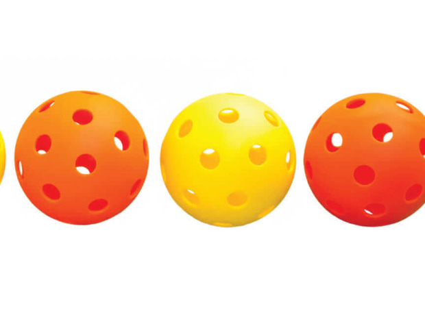 image of four perforated pickleballs in alternating orange and yellow colors lined up against a white background